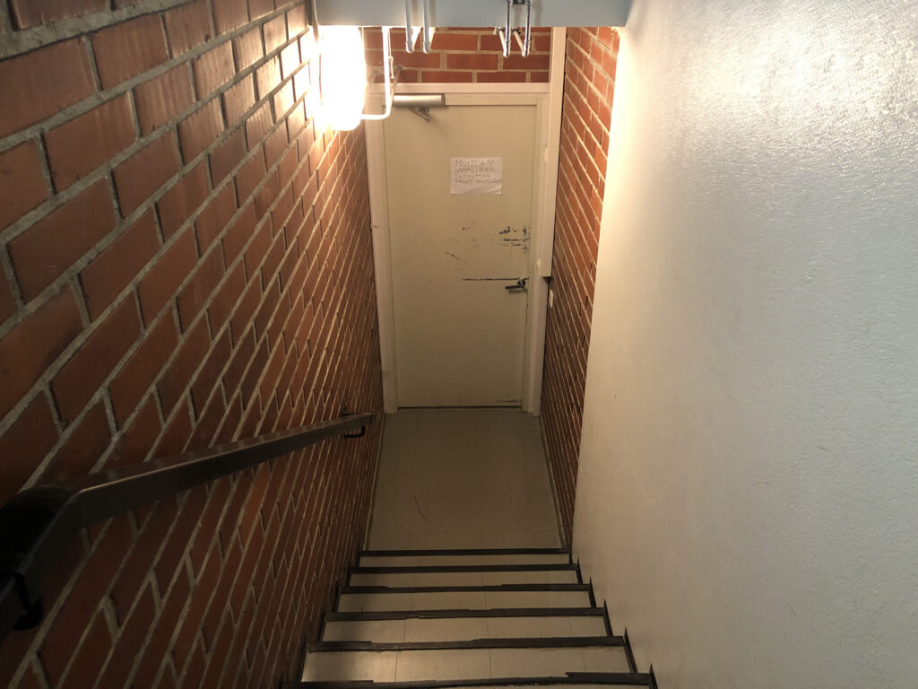 Door at the end of the stairs.